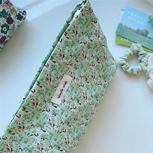 Detailed macro of floral cotton makeup bag with green print and a zip closure