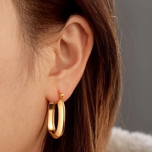 Polished 18K gold-plated geometric oval hoop earrings worn by a female model