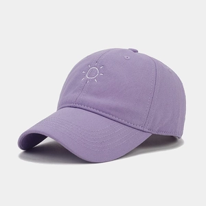Detail of purple canvas baseball cap with white embroidered sun pattern and curved brim