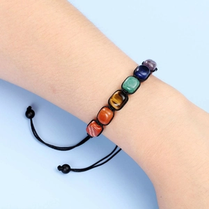 Handmade braided chakra bracelet with colorful natural stones on a model's wrist