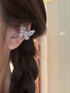 Detail of elegant silver butterfly ear cuff with sparkling zircons on a model's ear