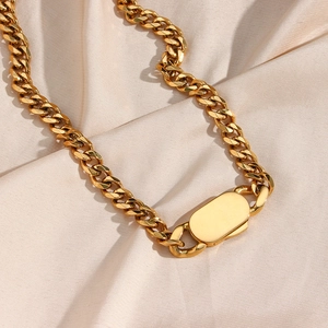 Golden chunky curb chain necklace with rectangular clasp on beige silk background