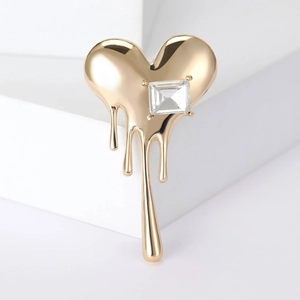 Polished gold melted heart brooch with sparkling zircon on a minimalist white stand