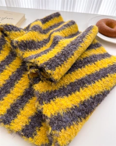 Macro detail of yellow and grey striped wool scarf showing soft knit texture and thickness