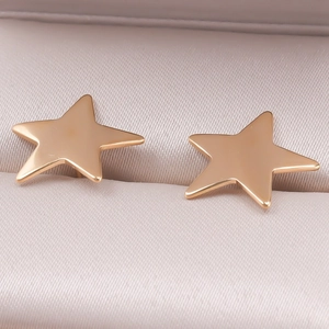 Macro shot of polished gold star stud earrings resting on a silk jewelry box lining