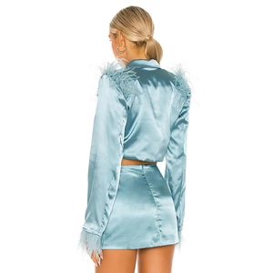Ensemble satin bleu clair avec plumes sur le blazer court et jupe à taille haute