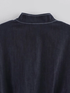 Close-up detail of white contrast stitching on the collar of a dark blue denim jacket
