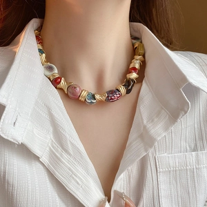 Close-up of ethnic ceramic flower necklace with colorful painted beads and golden metal accents