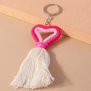 Close-up of handmade pink knitted heart keychain with elegant cream tassels and metal ring