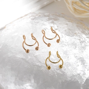 Three gold U-shaped non-pierced stainless steel septum nose rings on ice texture surface