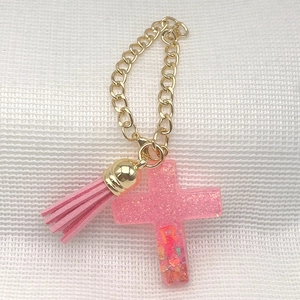 Pink glitter resin cross pendant with gold chain, tassel and letter R charm detail