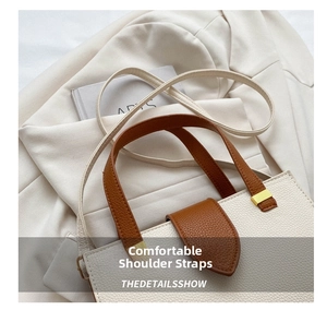 Detail of contrast-color leather tote with pebbled texture and gold metal hardware