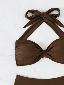 Detalle de bikini marrón oscuro con copas fruncidas sobre fondo de mármol blanco