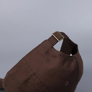Detail of adjustable brass buckle and premium cotton twill texture on brown baseball cap