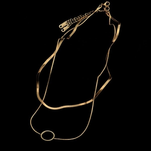 Detail shot of a layered gold snake chain necklace with a hollow circular pendant