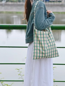 Outdoor shot of a classic green and purple plaid canvas tote bag with a soft texture