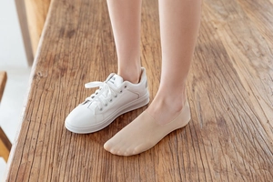 Breathable beige invisible low cut cotton sole sock worn with white sneakers on wood surface
