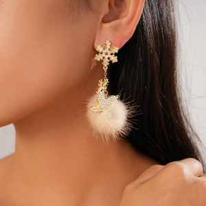 Detail of Christmas earrings featuring golden snowflake, reindeer with rhinestones and fur pompon