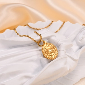 Macro view of golden oval pendant necklace with sunburst relief on white stone