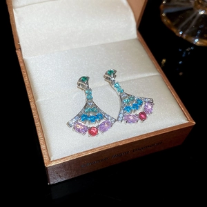 Macro shot of colorful fan-shaped zircon earrings with gemstones in a jewelry box