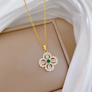 Detailed macro view of a gold clover pendant with sparkling zircon and green center stone