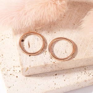 Detail of rose gold stainless steel seamless rings on textured stone with a feather