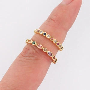 Detalle de los ajustes de circonitas de colores en dos anillos geométricos minimalistas dorados