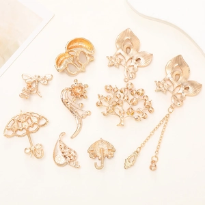 Golden metal DIY charms including butterfly, tree, leaf and umbrella designs on light background
