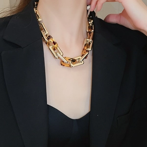 Dettaglio di una collana a catena dorata con maglie leopardate su una modella