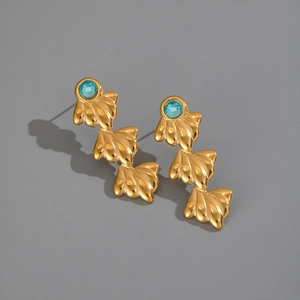 Détail macro de boucles d'oreilles coquillage plaquées or 18K avec zircon turquoise