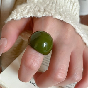 Detail of a thick olive green resin ring with a smooth finish worn on a finger
