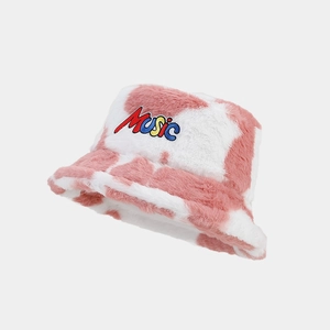 Detailed close-up of pink and white cow print faux fur bucket hat with MUSIC embroidery