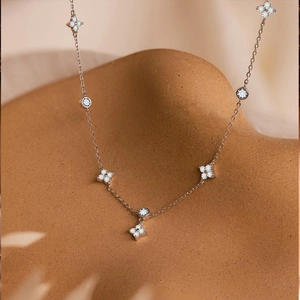 Detail der Kleeblatt-Halskette mit Pavé-Diamanten auf elegantem orangefarbenem Ständer