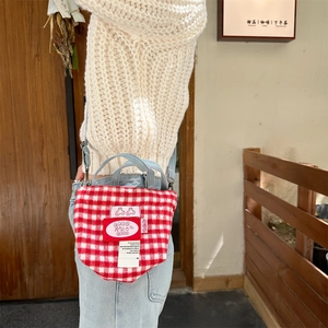 Detail of red and white plaid woolen tote bag featuring cherry patch and denim straps