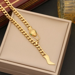 Detailed view of a gold snake-themed Cuban chain necklace with green stone eyes in a box