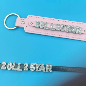 Close-up of DIY leather wristbands in pink and black with sparkling rhinestone letters