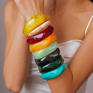 Close-up of stacked colorful resin bangles in square and oval shapes on a model's wrist