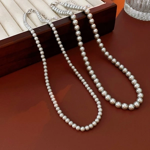 Detailed view of silver-gray and white pearl necklaces with adjustable metal lobster clasps