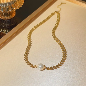 Gold leaf-shaped link necklace with a white baroque pearl pendant in elegant close-up