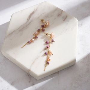 Detail of S925 silver fringe earrings with natural pearl and purple mica on marble