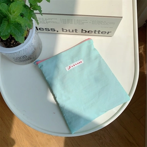 Mint green nylon cosmetic bag with pink zipper on white table with green plants