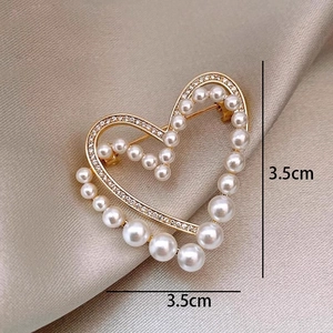 Macro shot of gold heart brooch with pearls and crystals measuring 3.5cm on satin