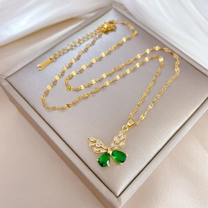 Close-up of butterfly pendant necklace with green and white zircons on a satin base
