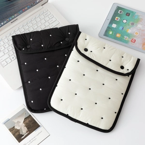 Detailed view of quilted laptop sleeves in black and polka dot with dual button closure