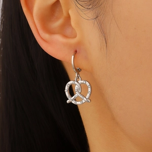 Dettaglio di orecchini pretzel in argento con zirconi scintillanti sul modello