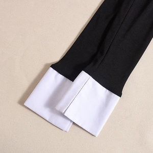 Détail de la manche en tricot côtelé avec revers blanc sur haut body noir