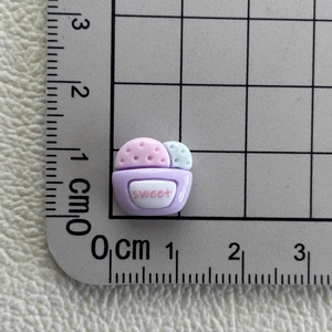 Macro shot of a 1cm mini resin cupcake charm with sweet text on a measuring scale