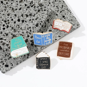 Set of five colorful enamel book brooches with funny quotes on volcanic stone background