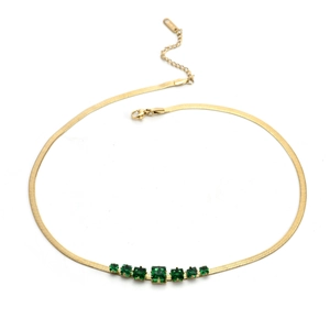 Flat gold snake chain necklace with seven emerald-cut green gemstones on white background