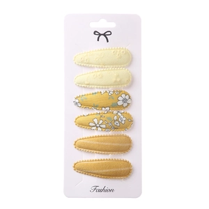 Set of 6 yellow fabric hair clips with floral and striped patterns on card
